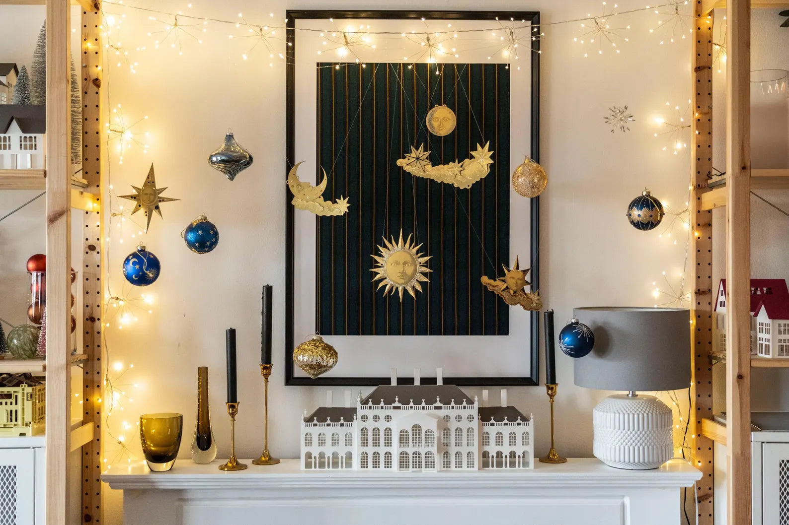 A decorative paper celestial garland displayed in a festive setting with gold stars, moons, and other celestial bodies strung across a room with Christmas lights and decorations.