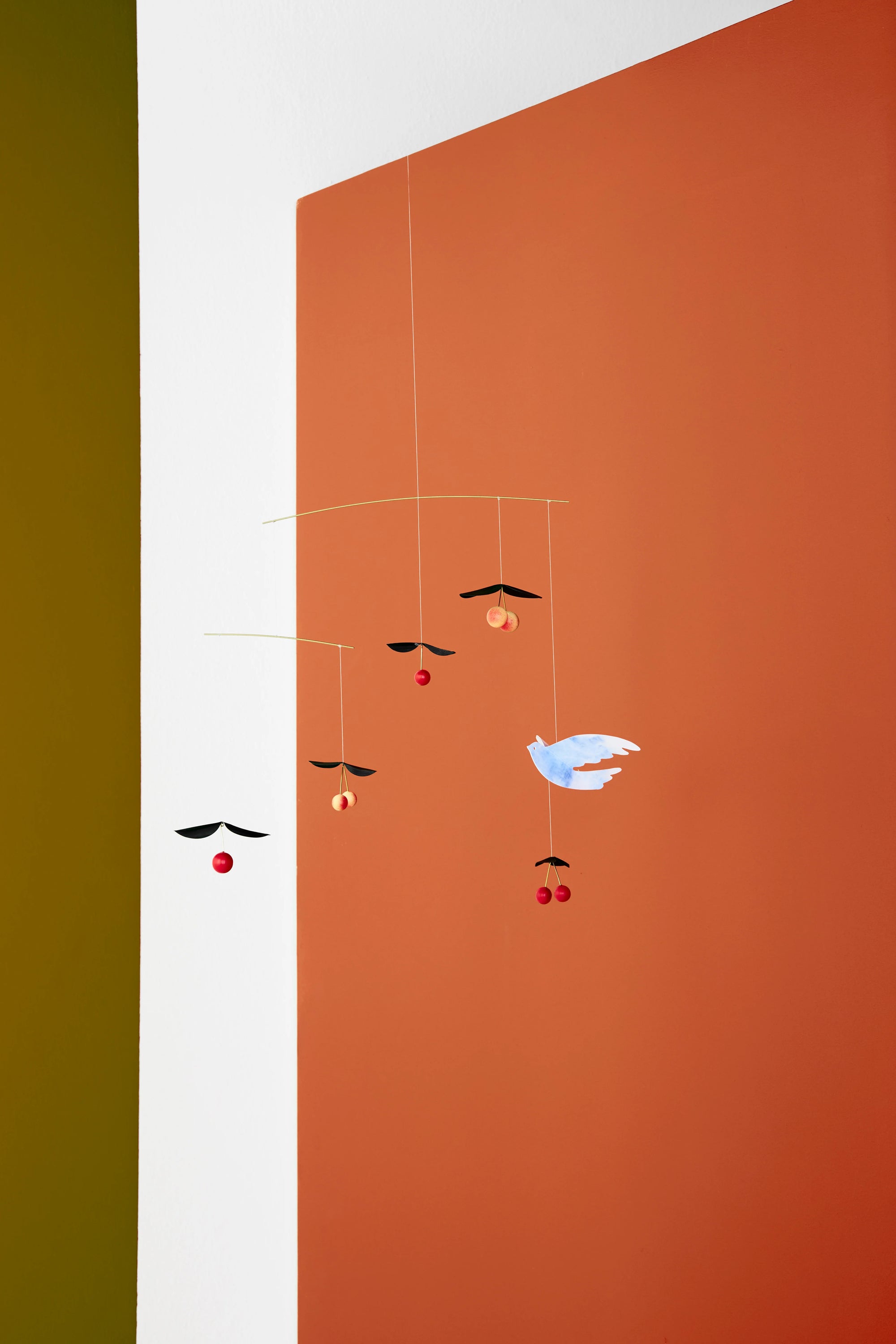 cherry and bird hanging mobile with geometric shapes on a divided background