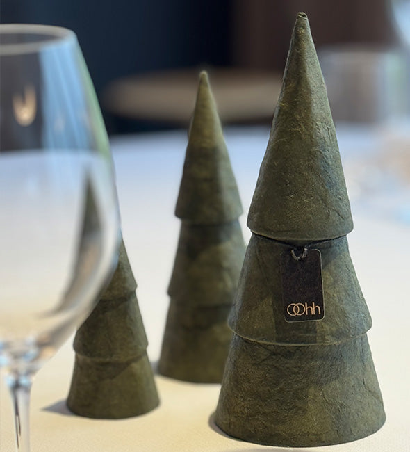 Three green felt Christmas tree coasters on a table with a glass of wine.