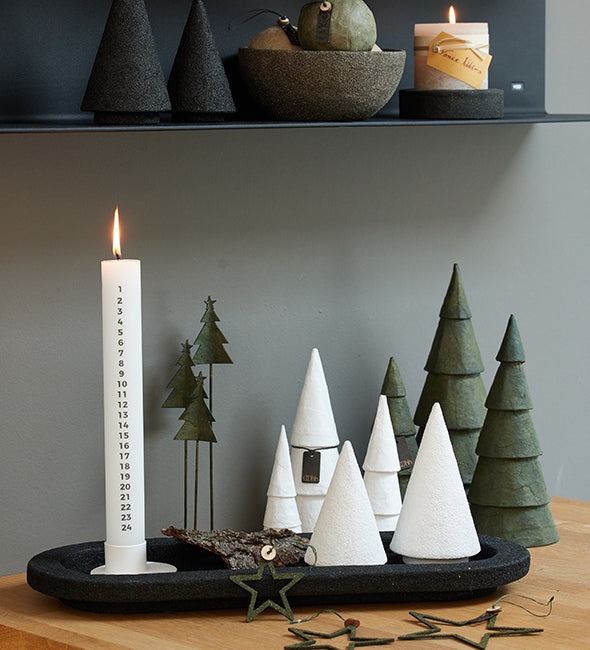 Decorative setup with candles, trees, and a star on a wooden surface.