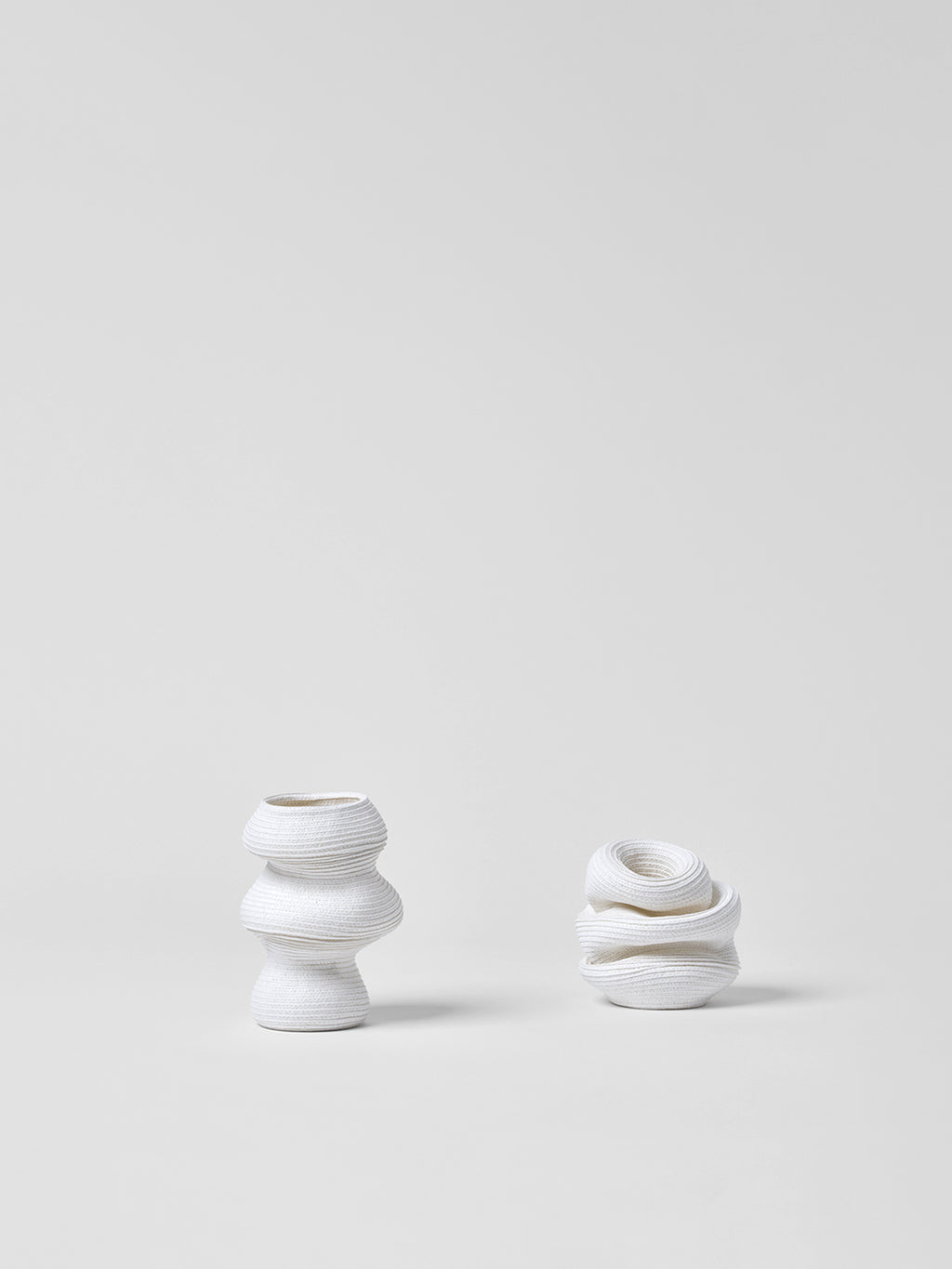 Two small white paper vases with textured design on a light gray background