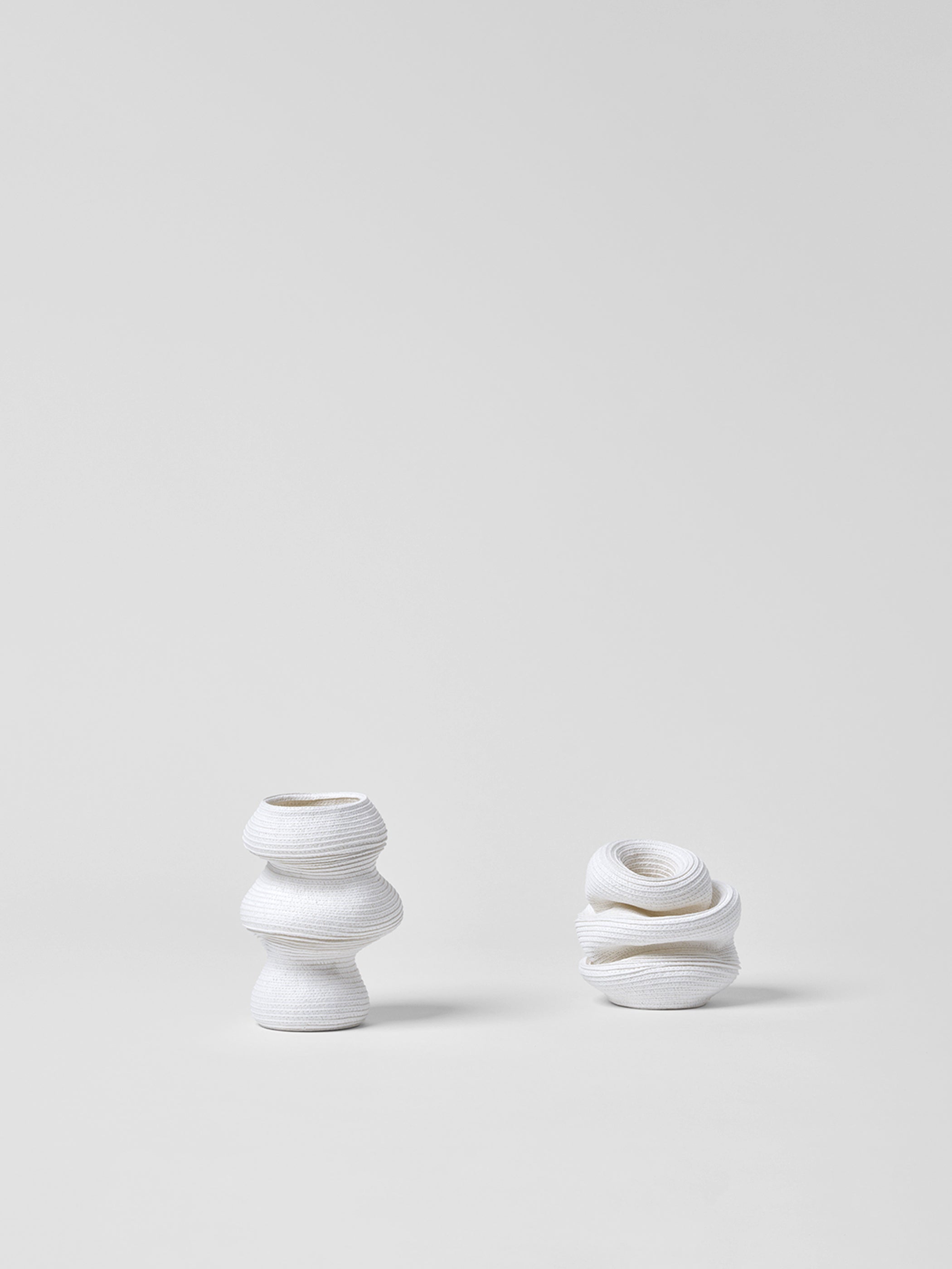 Two small white paper vases with textured design on a light gray background