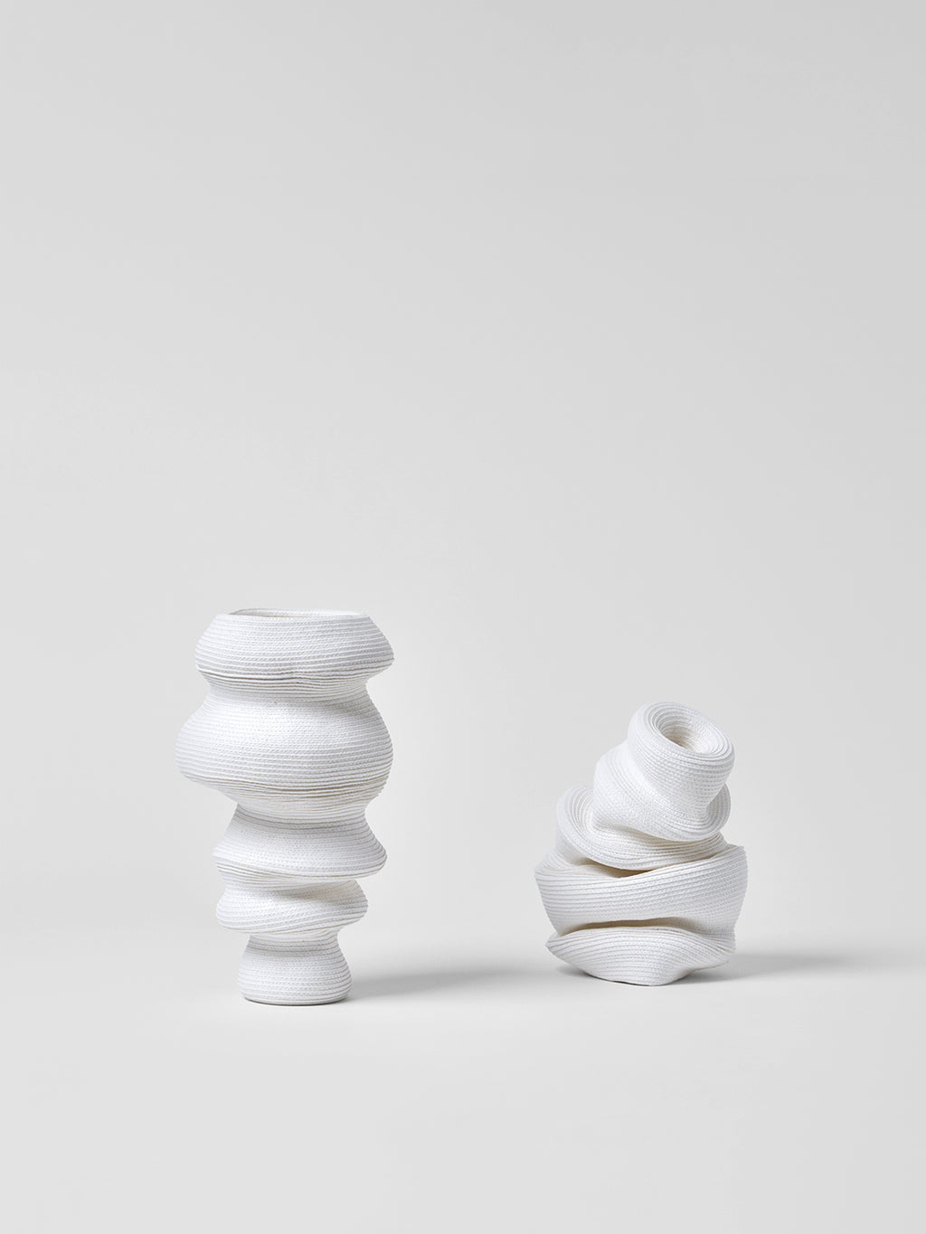 Two white paper vases with textured design on a light gray background