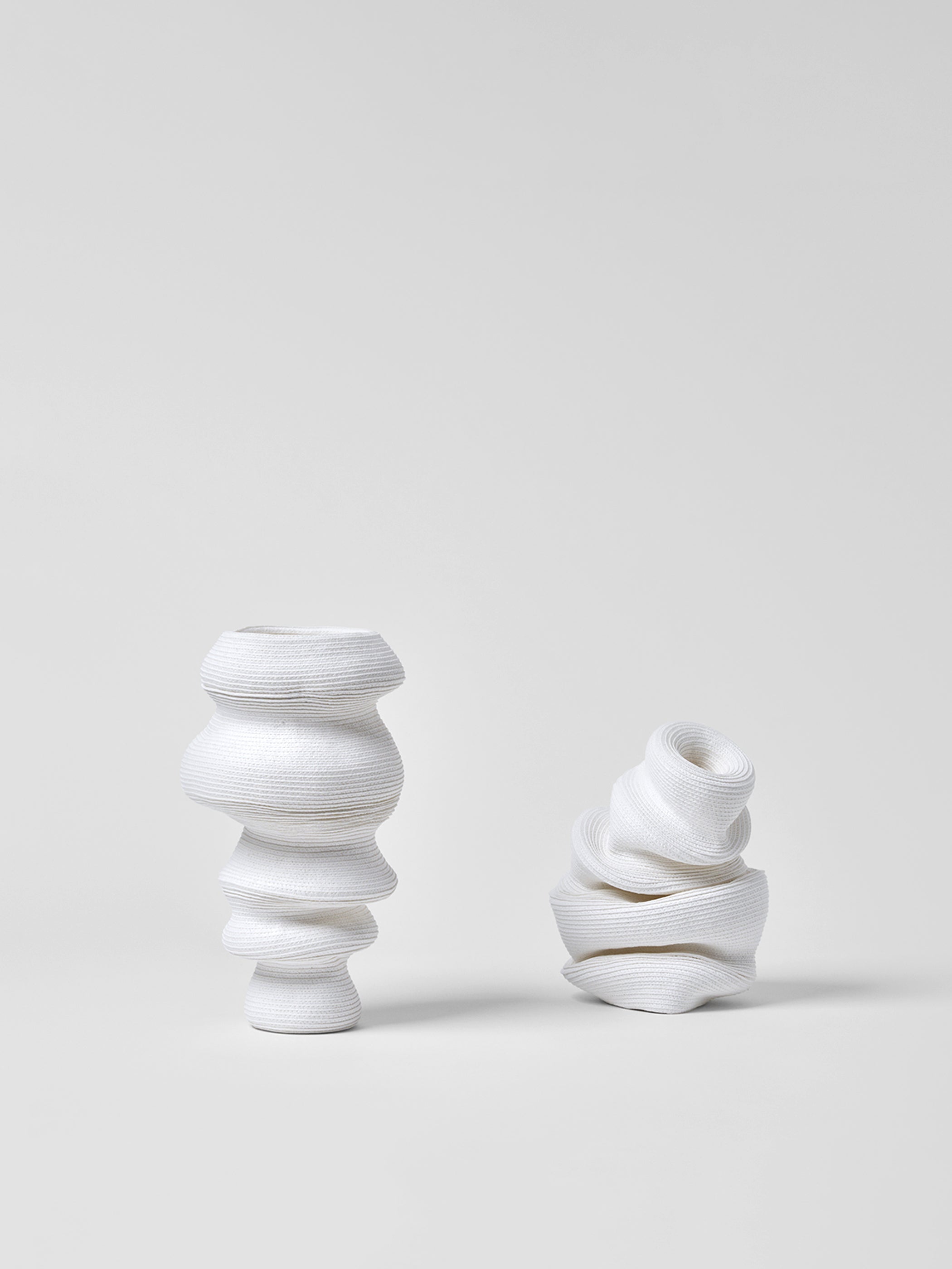 Two white paper vases with textured design on a light gray background