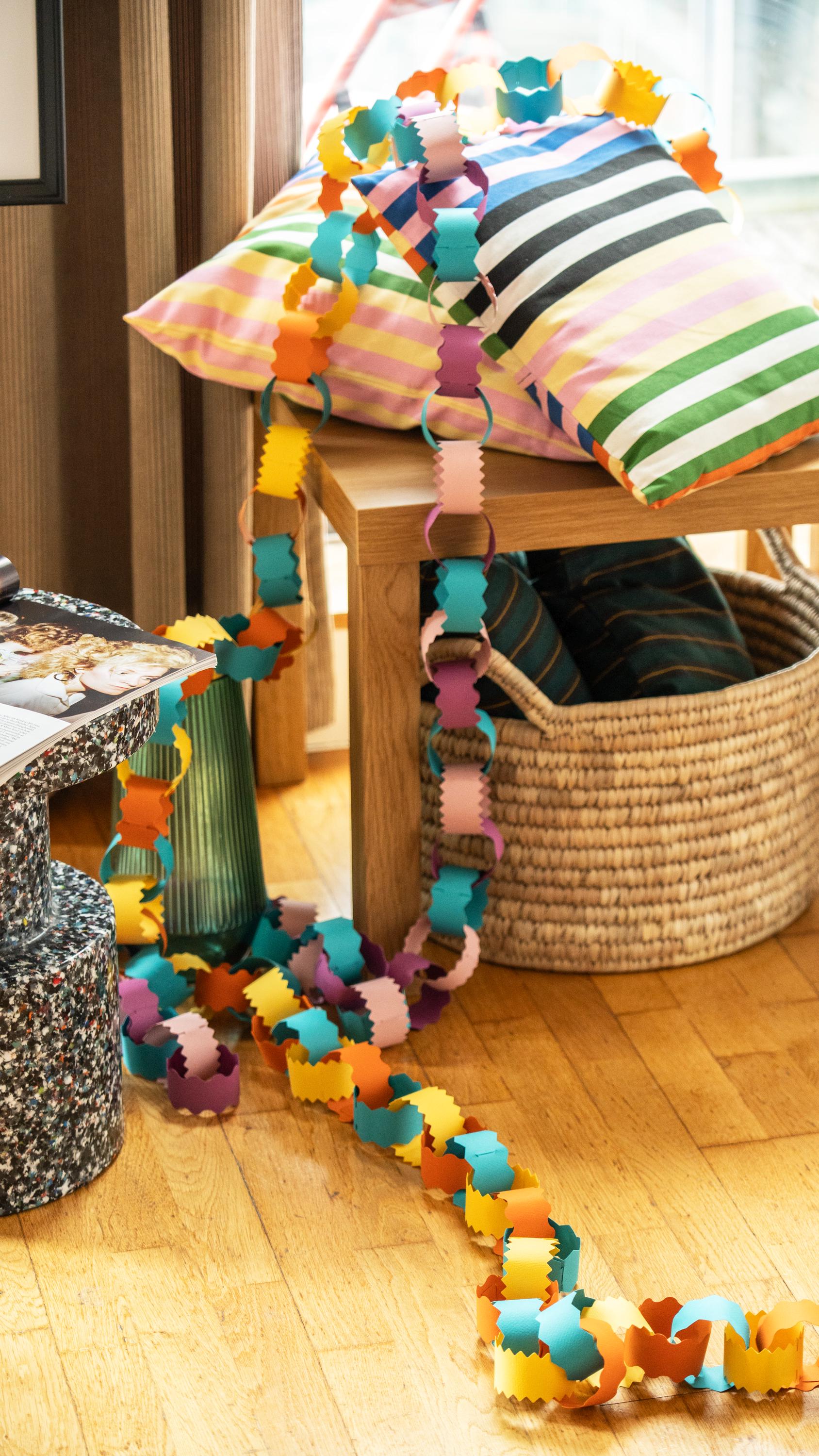 Colorful paper chain on a wooden bench with striped cushions