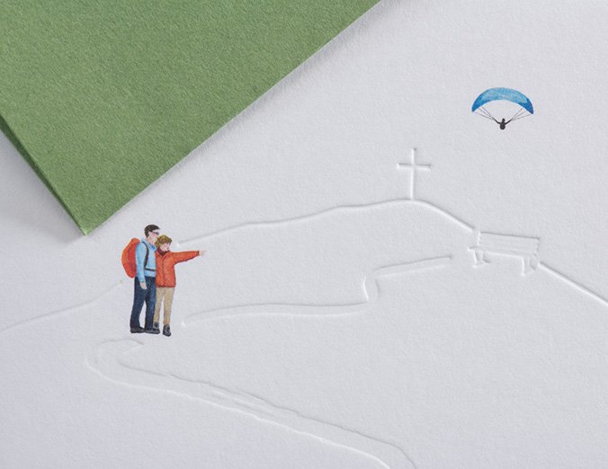 Two people standing on a snowy landscape with a paraglider in the sky.