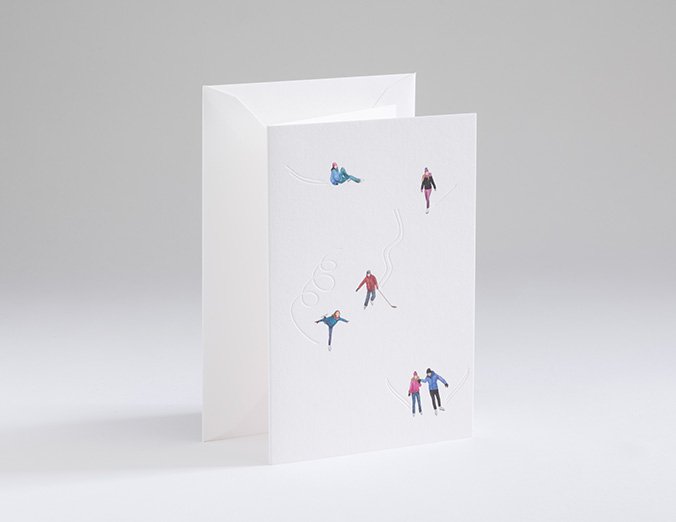Greeting card with miniature figures of people on skis and snowboards against a white background