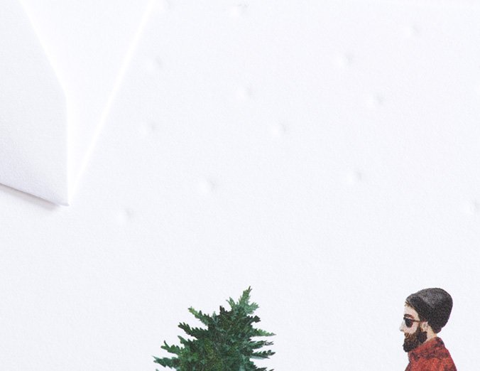 Man with a beard wearing sunglasses and a red sweater standing next to a small Christmas tree on a white background