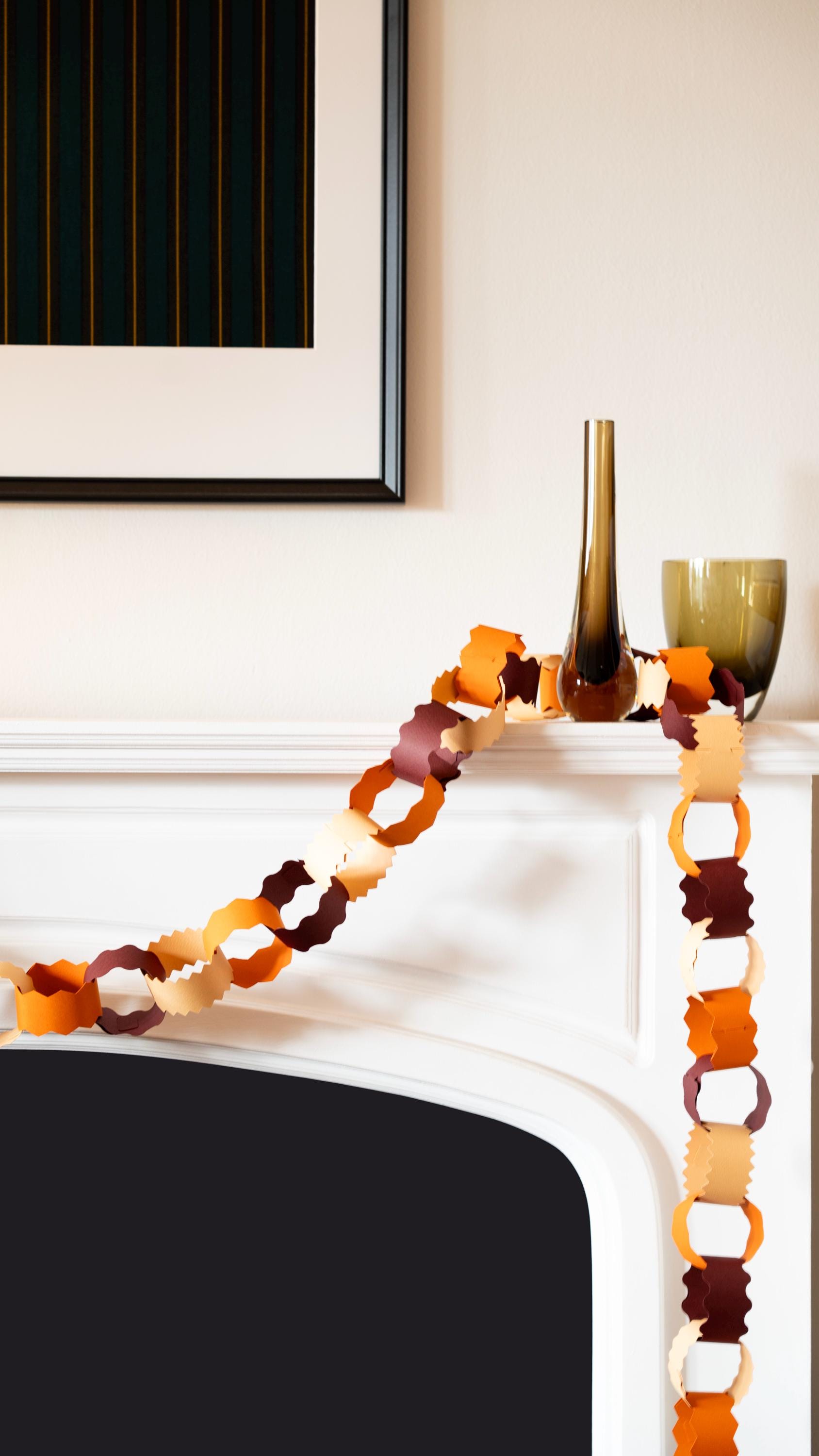 Decorative paper chain on a fireplace mantel with vases in the background.