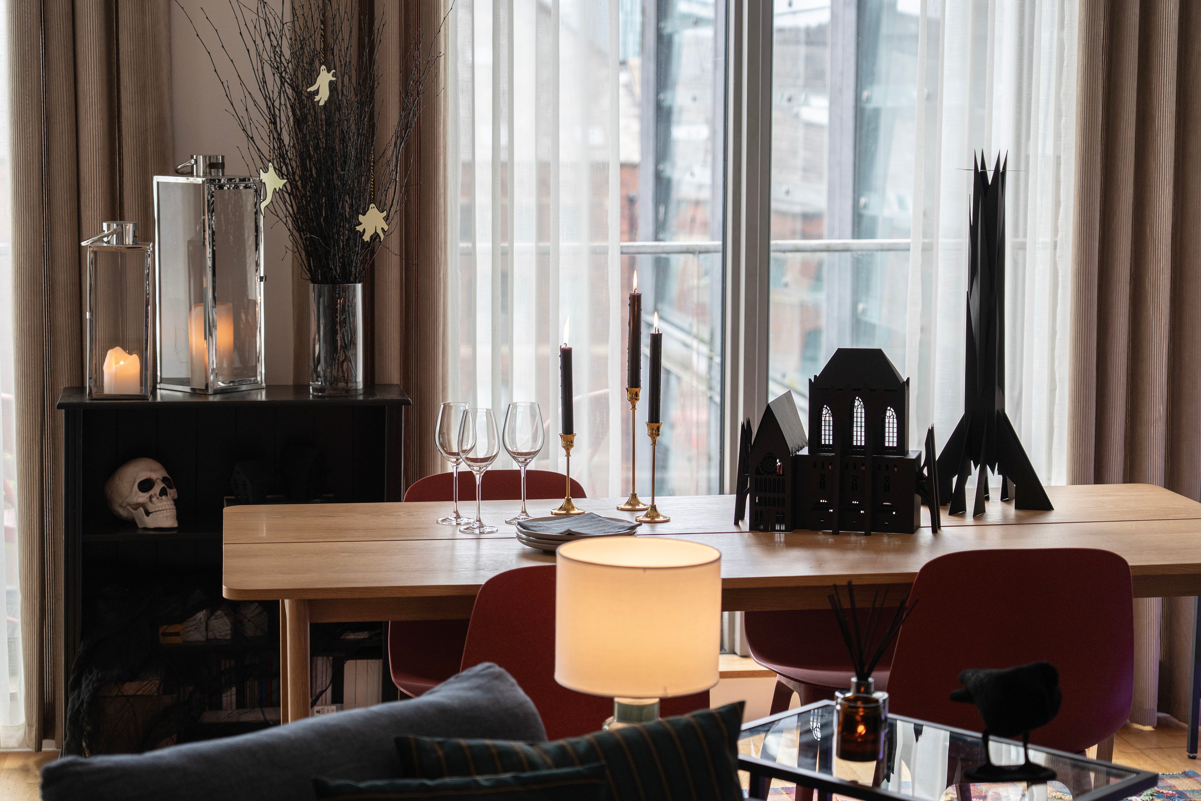 Modern dining room with a table, chairs, and Halloween decorations near large windows.