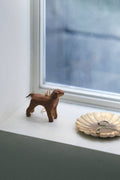 Small brown dog ornament on a windowsill with a shell and small object nearby.
