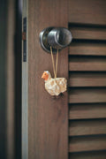 Decorative sheep ornament hanging on a wooden door handle.